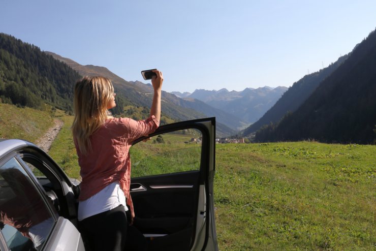 Una donna fotografa il paesaggio fuori dalla sua automobile